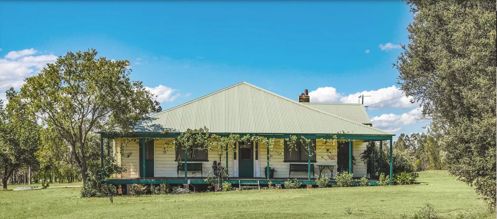 Historic farmhouse building with green porch and metal roof