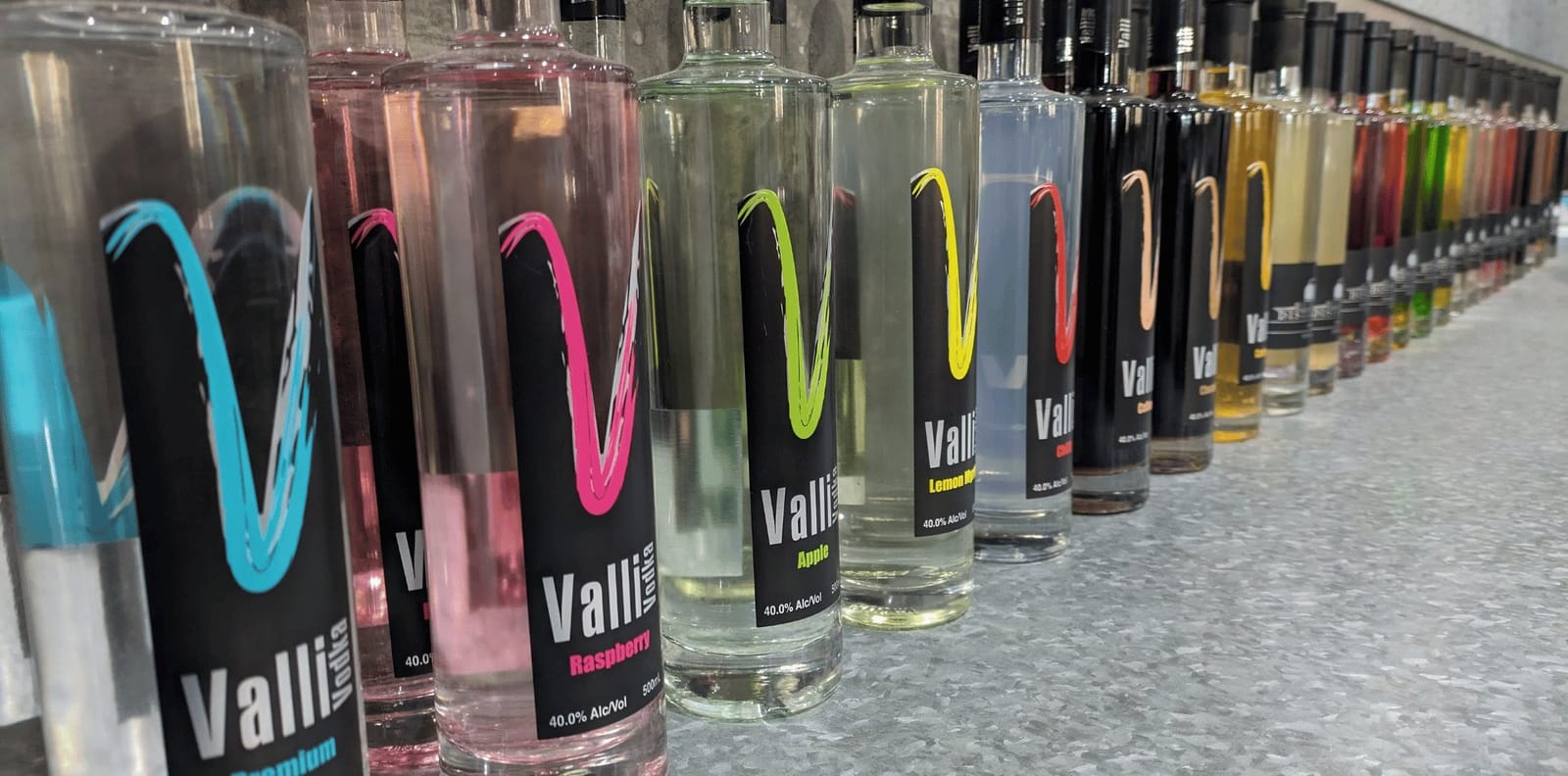 Array of Valley spirit bottles with diverse coloured spirit liquids