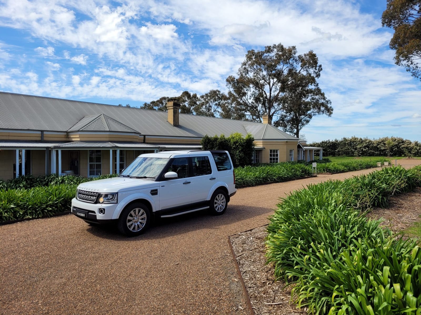 Hunter Gleann homestead exterior with driveway, gardens and a parked car