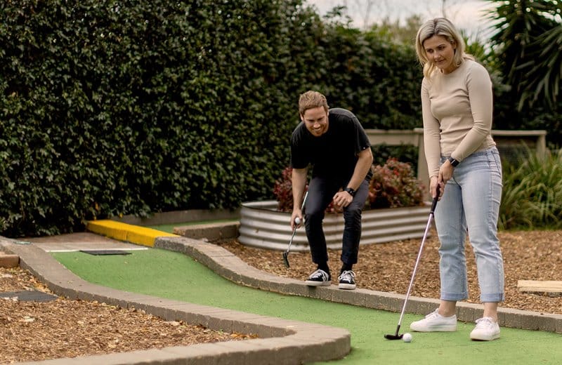 Two people playing a hole on the putt putt course