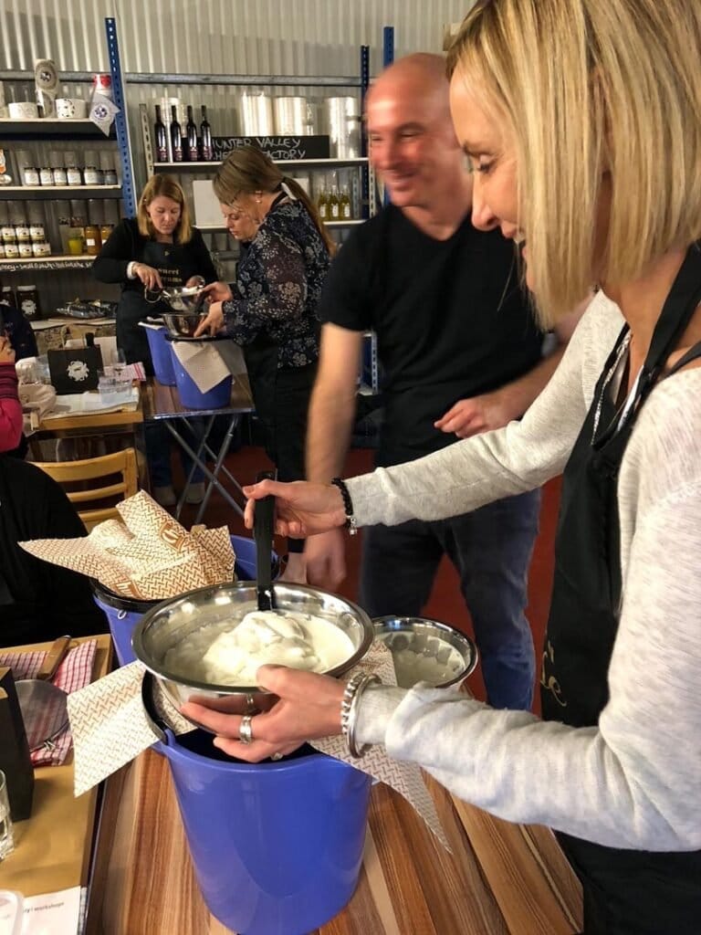 Visitors making fresh cheese at demonstration counter in venue
