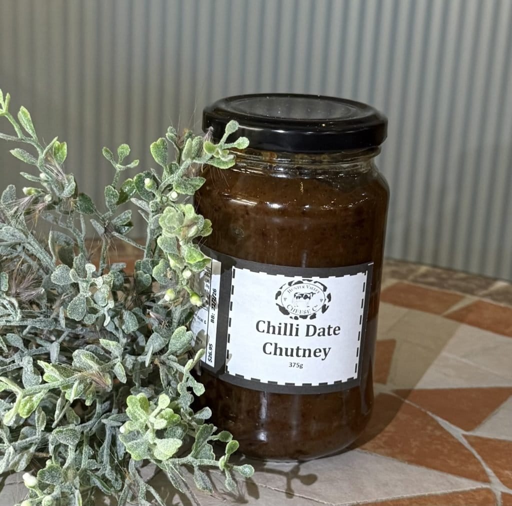 Jar of chilli date chutney next to fresh peppermint plant