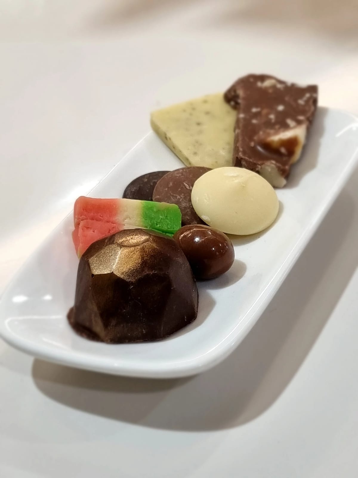 White plate of assorted hand-made chocolates and confectionery pieces