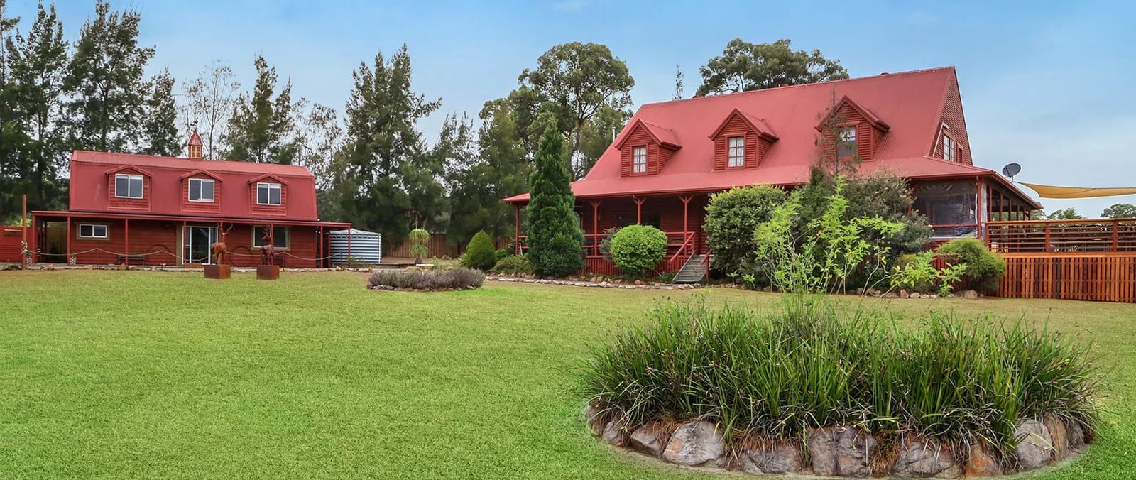 Red wooden lodge buildings with dormers set in green landscape