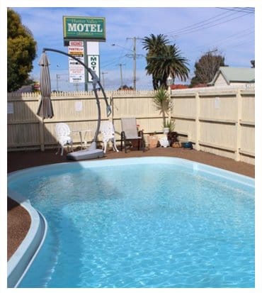 Outdoor swimming pool at Hunter Valley Motel with the motel signage and boundary fence behind it, Cessnock.