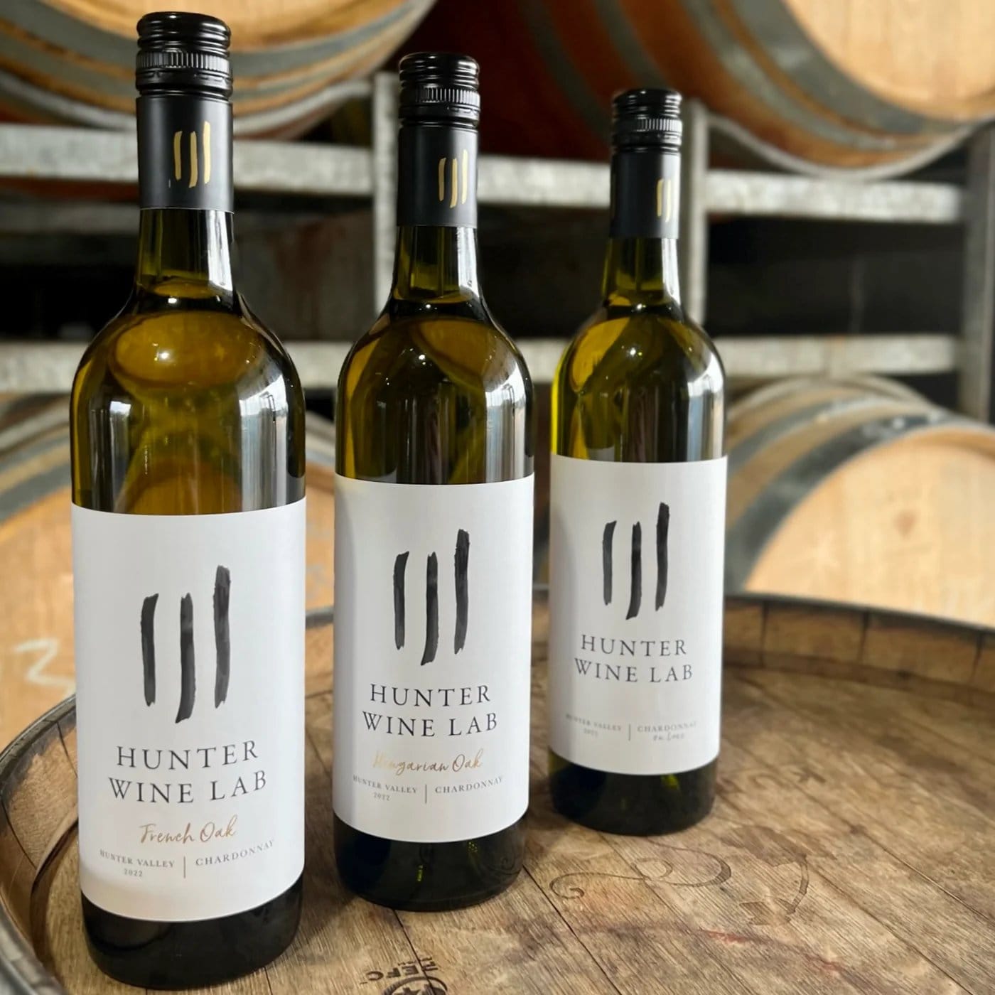 Three bottles of Hunter Wine Lab wine lined up on a barrel