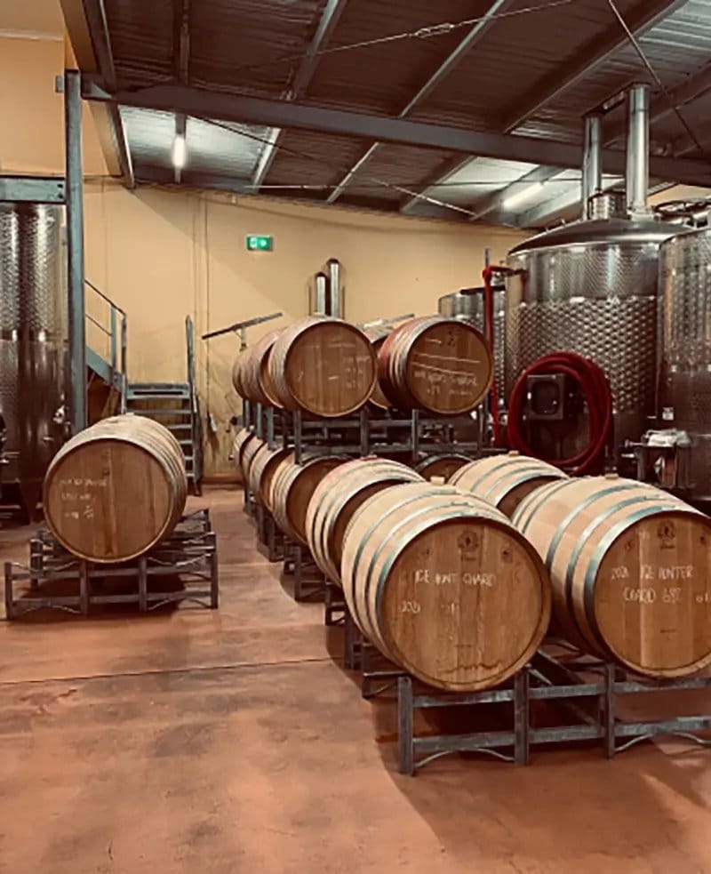 Wine barrel storage room with wooden barrels and stainless steel fermentation tanks