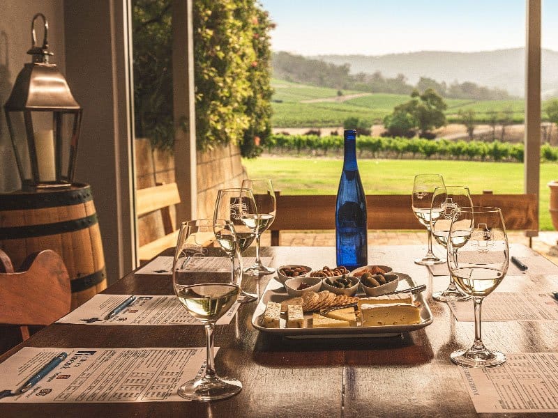Tasting room interior with wine glasses, cheese and vineyard view through window