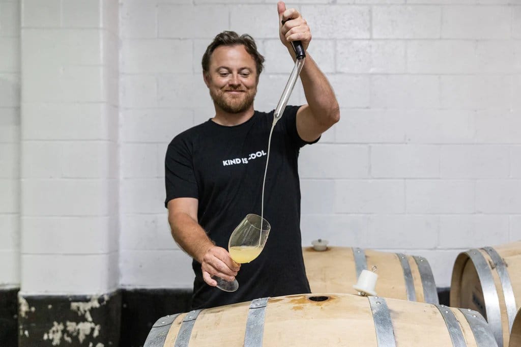 Winemaker sampling wine directly from barrel using a wine thief