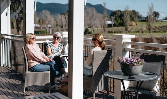 Three guests seated on the cellar door terrace with the Brokenback Range behind