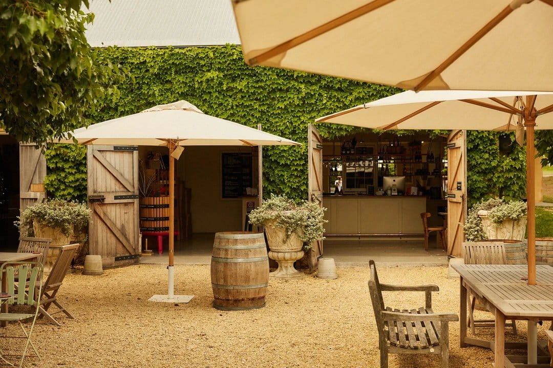Outdoor tasting area with umbrellas, barrels and wooden tables