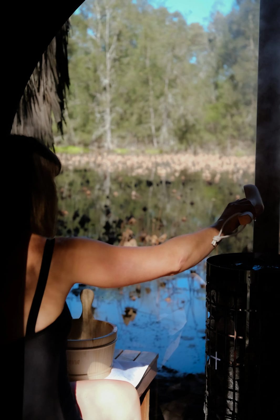 A guest at the outdoor barrel sauna beside the pond
