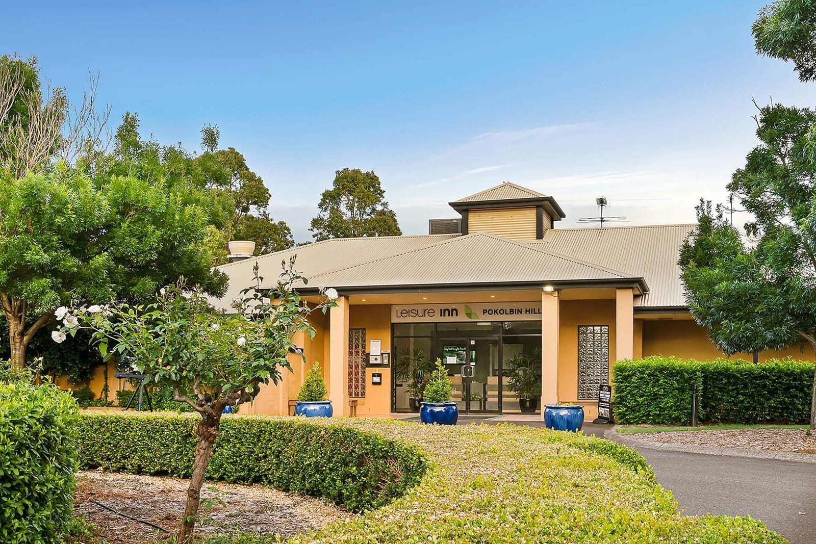 The Leisure Inn Pokolbin Hill entrance and reception, with clipped hedges and blue pots at the door