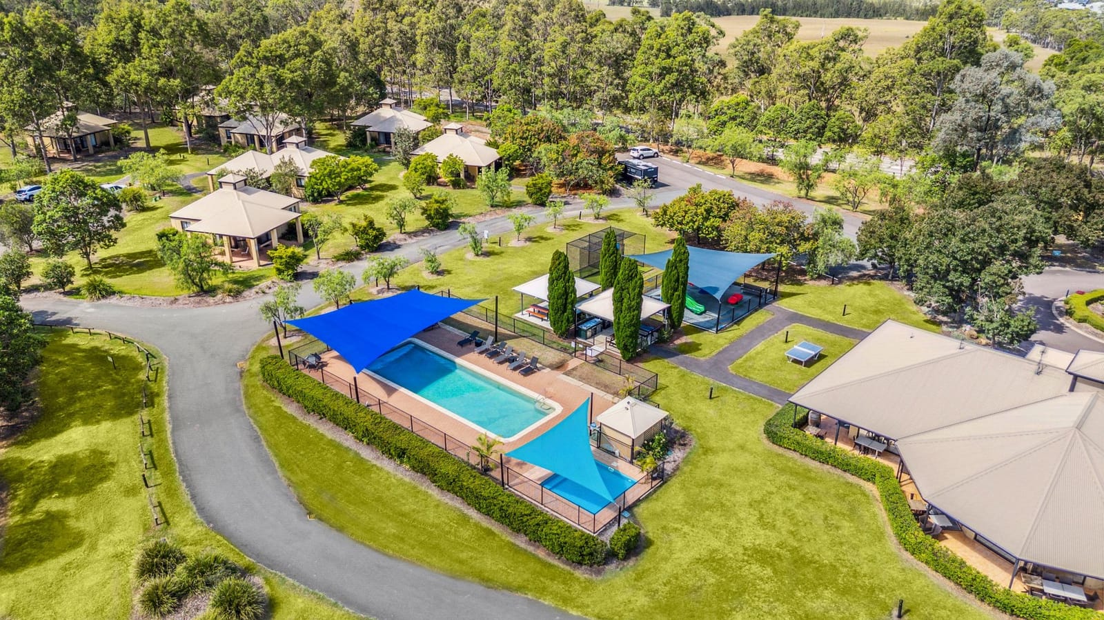 An aerial view of the pool, shade sails, tennis court and villas across the Leisure Inn grounds