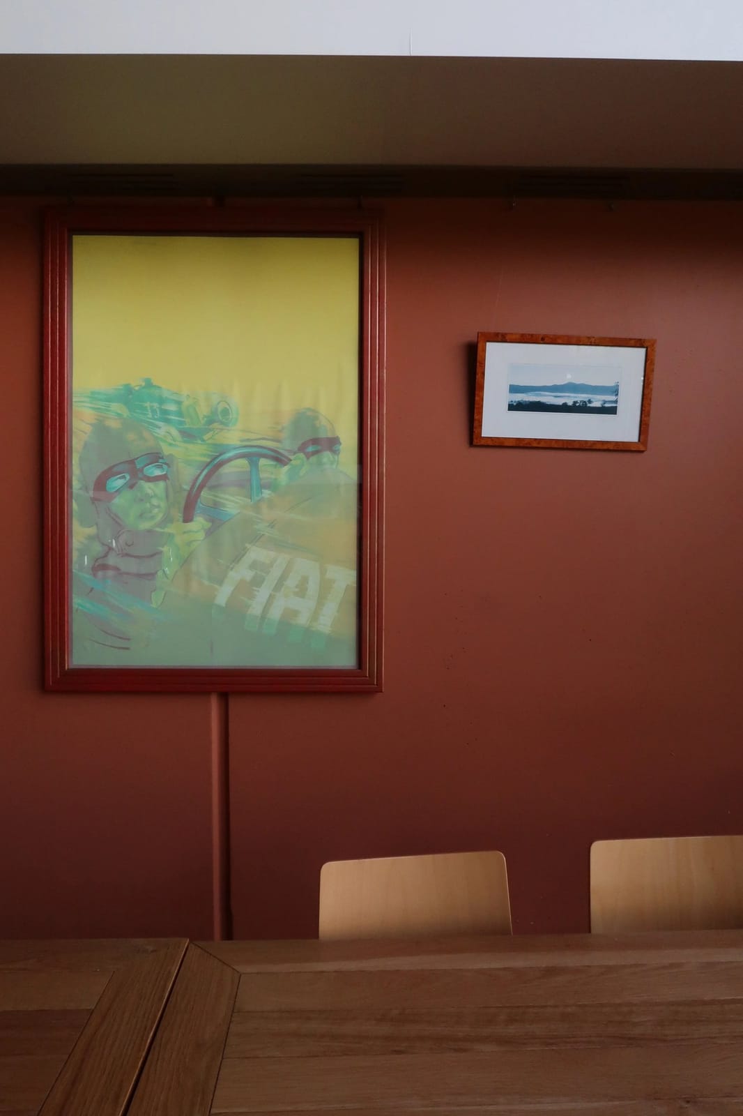 Dining room at Lillino's Bar and Trattoria with framed artwork on a terracotta wall and a wooden table setting