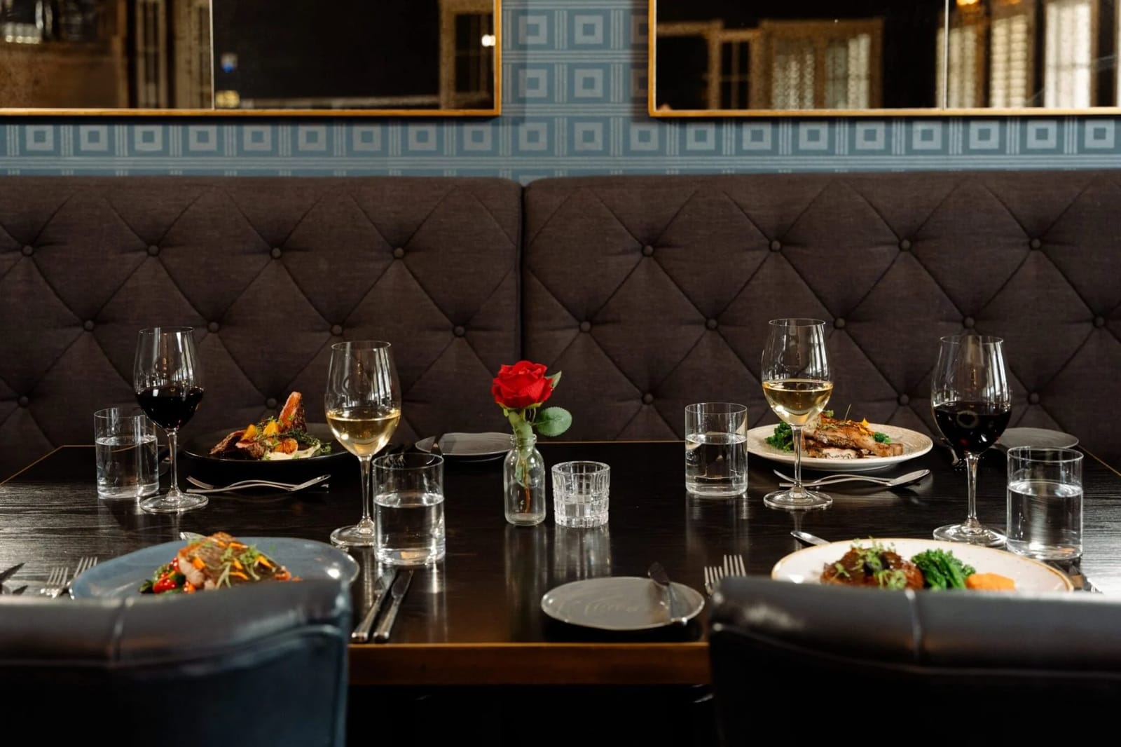 Window-side table for two at Locavore Restaurant set with wine glasses and a rose, looking onto the verandah.