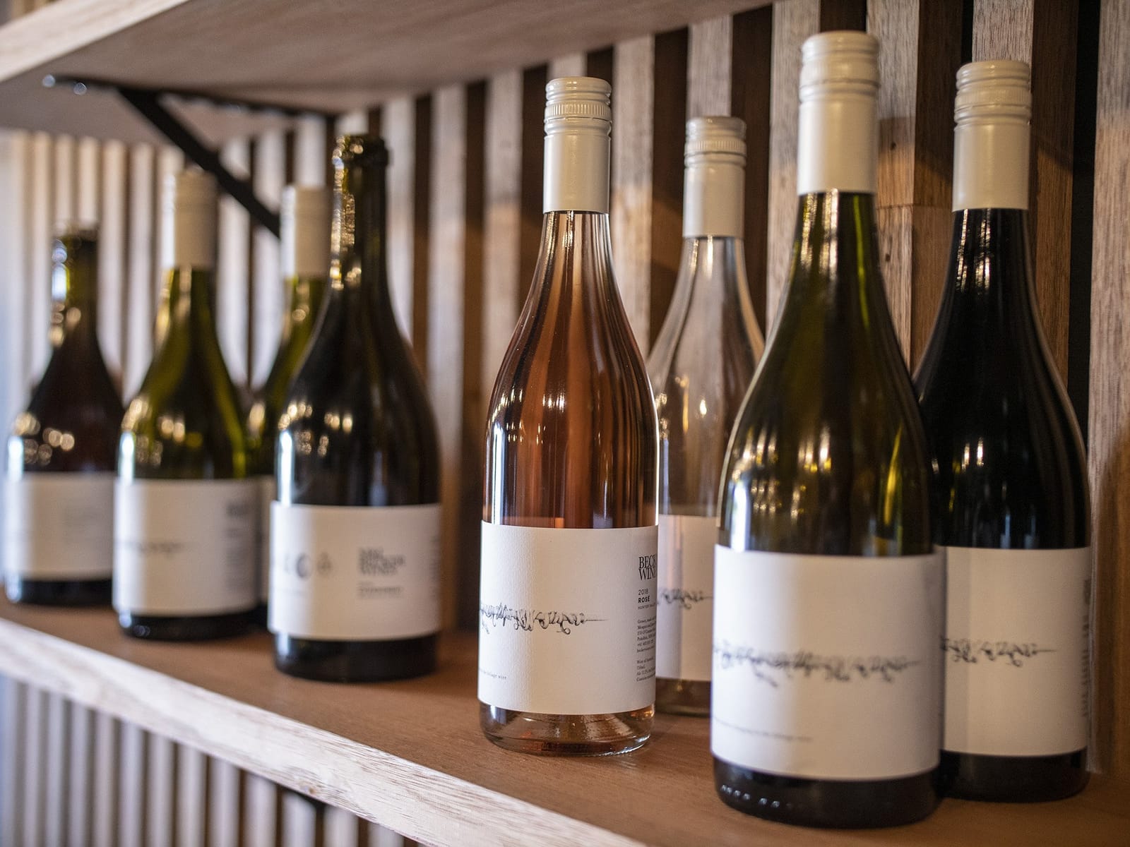Wine bottles displayed on wooden shelf with vintage interior