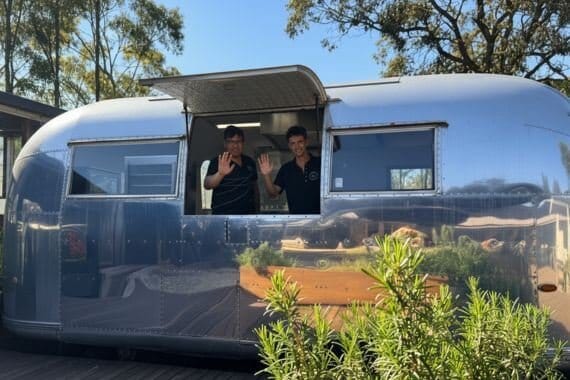 Mangia at Saddler's vintage Airstream kitchen, parked among trees with staff serving through its windows.