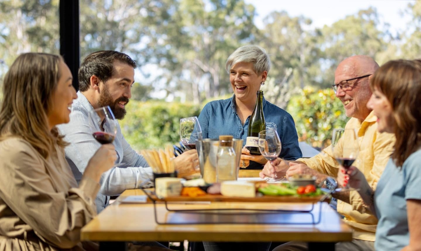 Diners at outdoor tables in front of Saddler's Creek's cellar door and Bluegrass Room, with a musician performing nearby.
