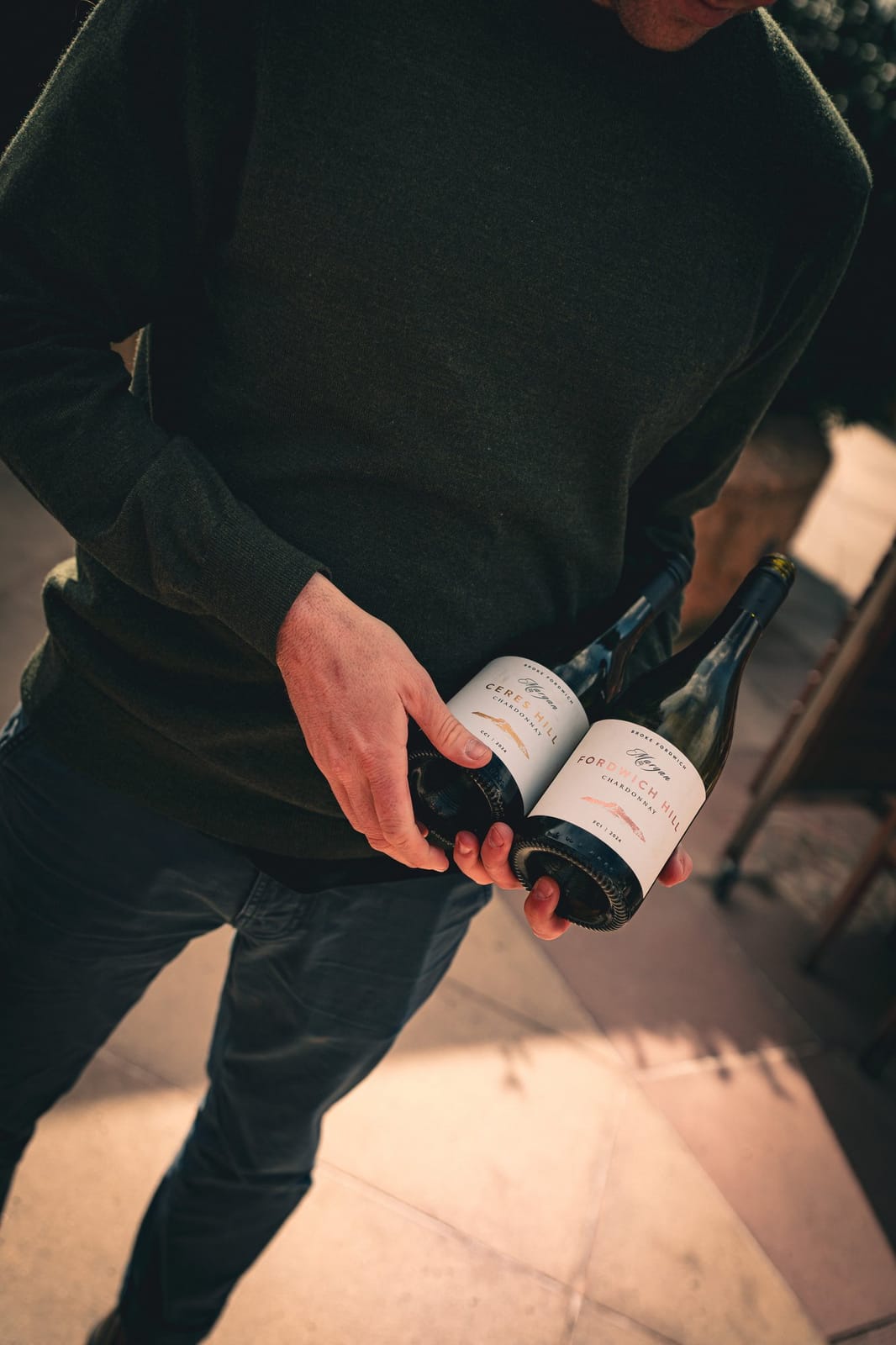 Two wine bottles held in hands with visible labels