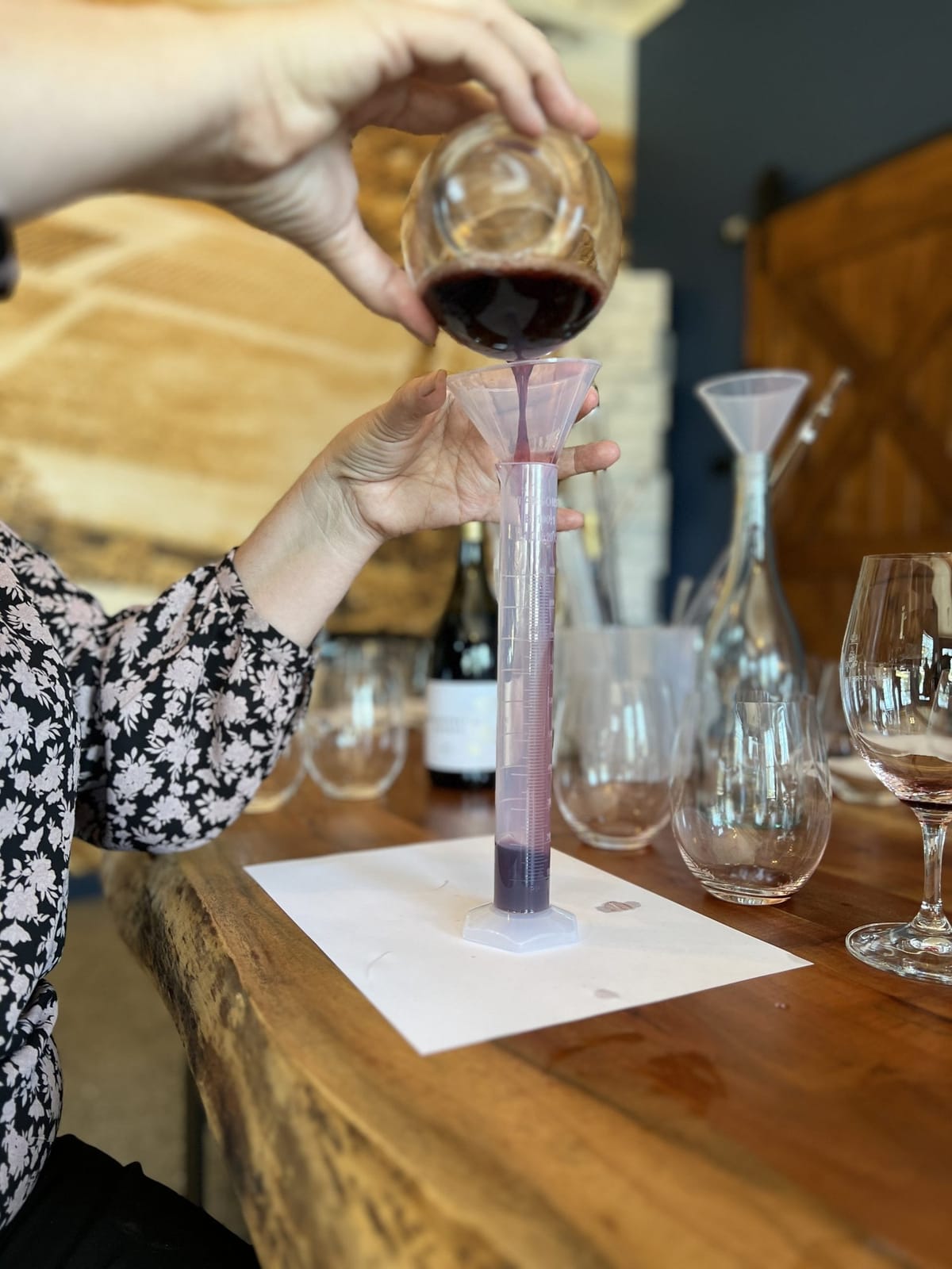 Hands evaluating wine colour using clear measurement glass and scale