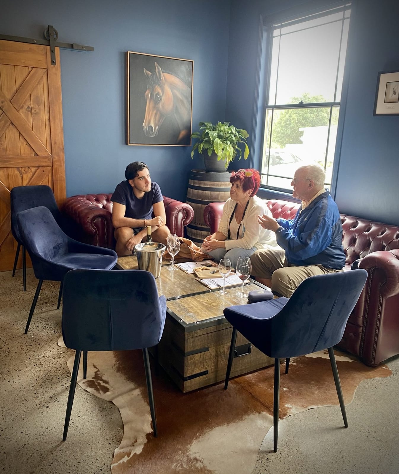Three visitors tasting wine in lounge with burgundy leather chairs