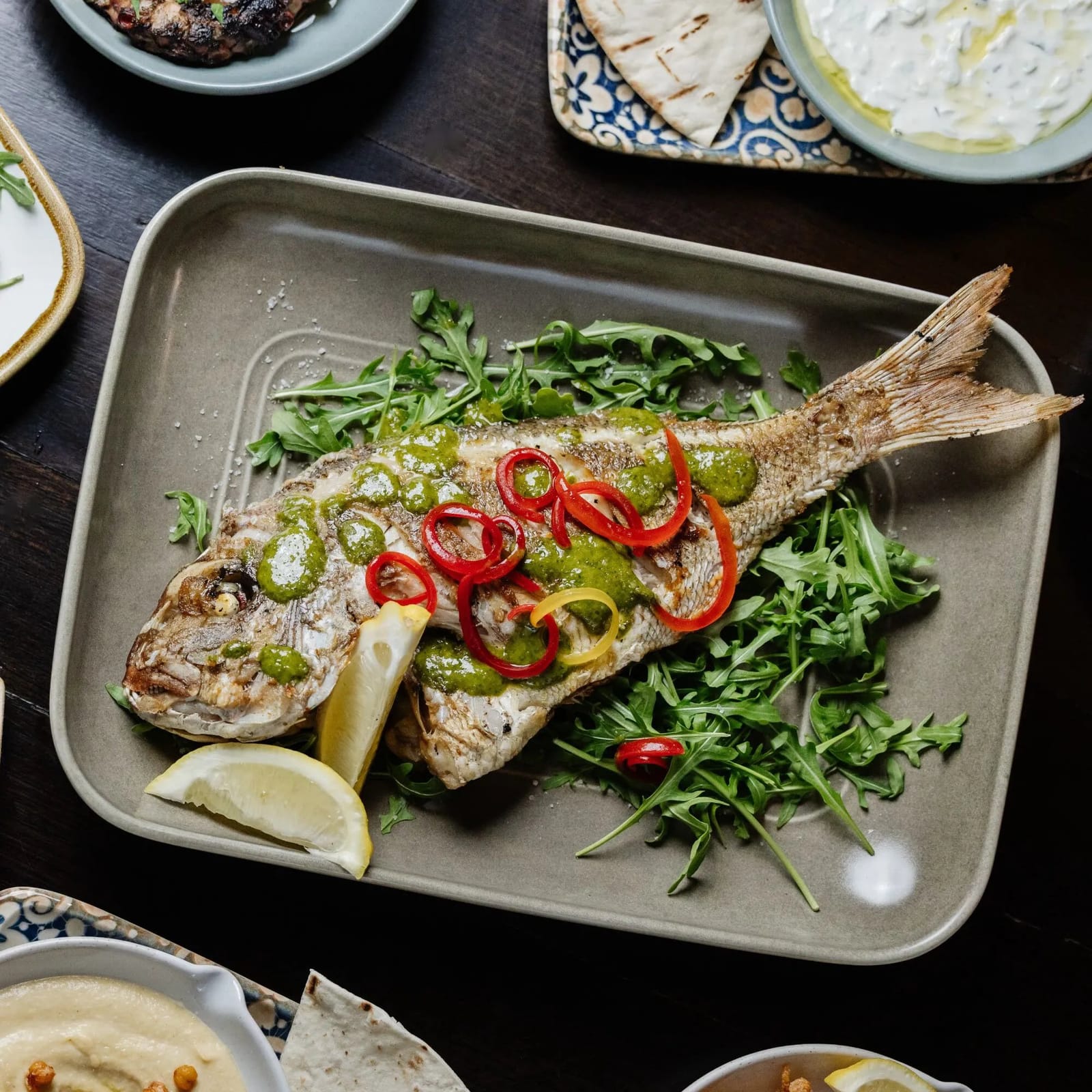 A whole grilled fish with a shared mezze spread at dinner