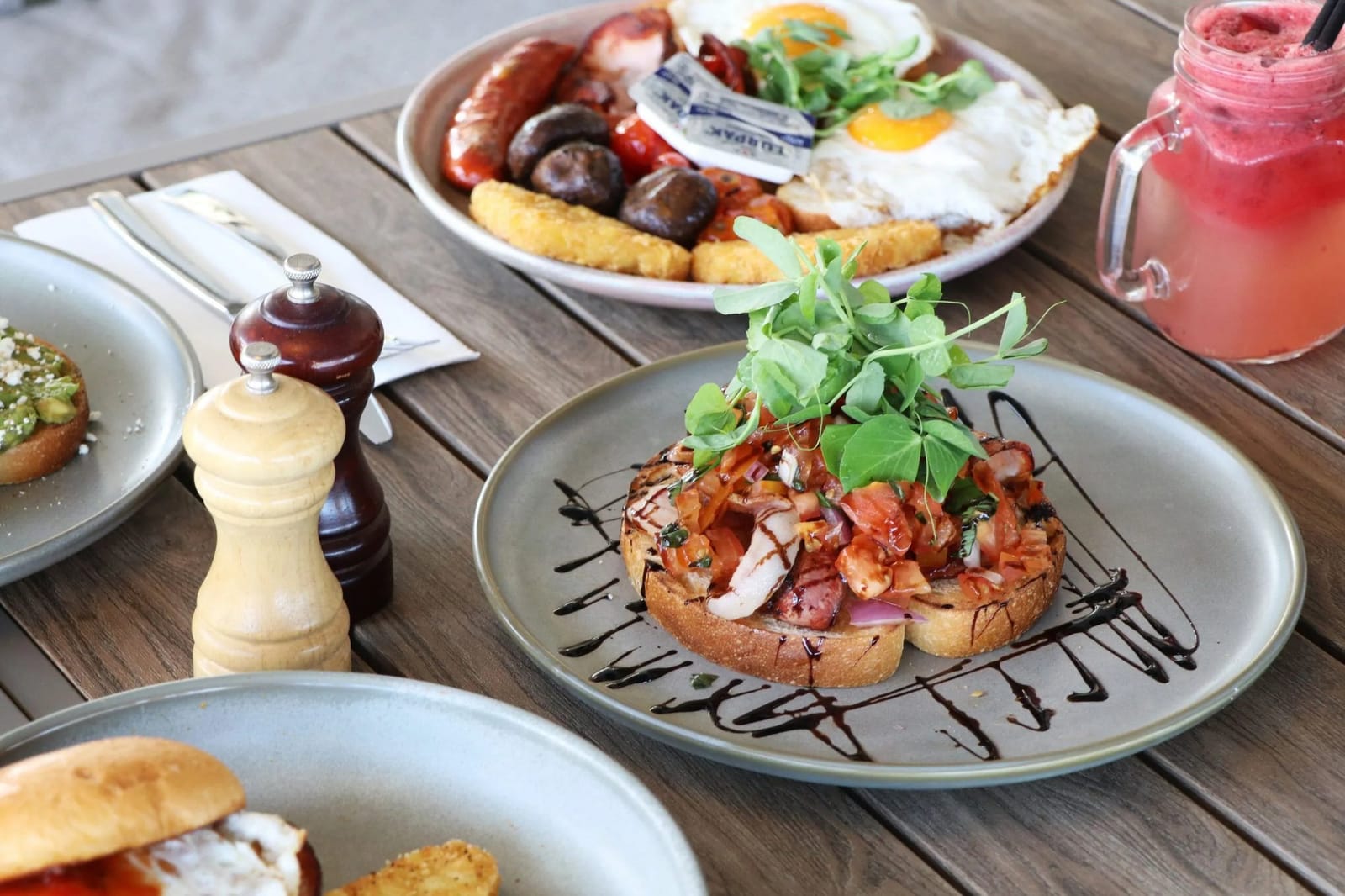 A breakfast spread at Mezze: bruschetta, a big breakfast plate and a berry smoothie