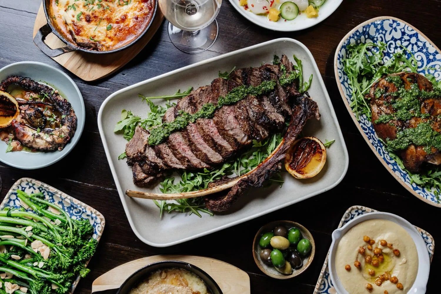 A shared dinner spread at Mezze, including a tomahawk steak and mezze plates