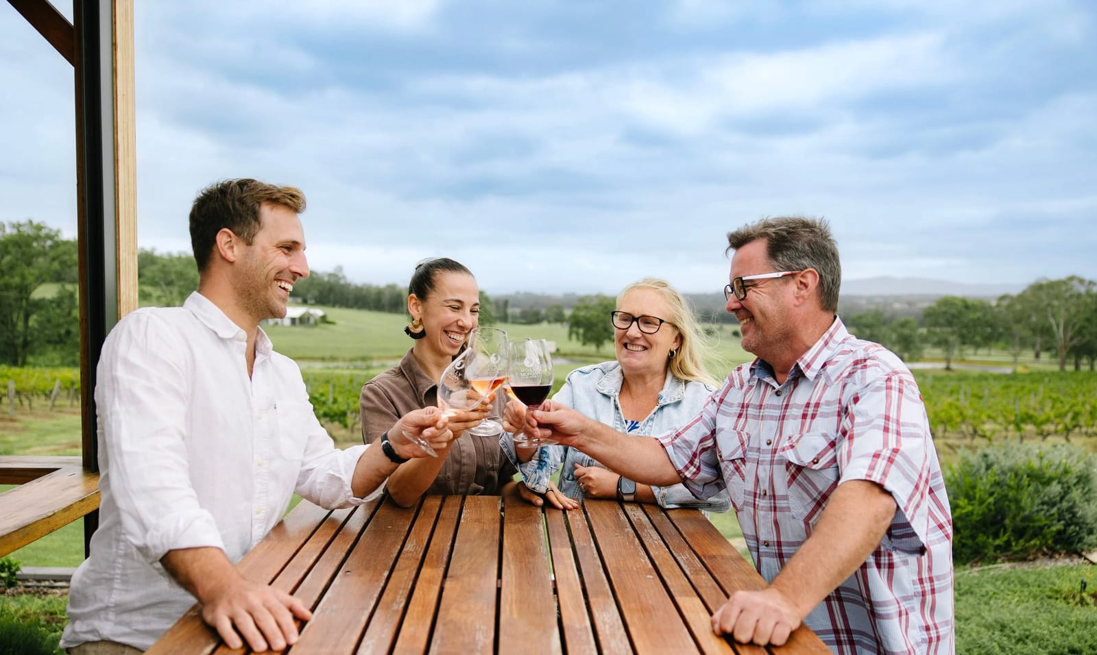 Four guests raising glasses of rose and red at the cellar door table