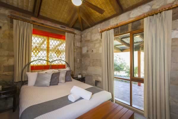 A bedroom with sandstone walls and a stained-glass window at Monkey Place Country House