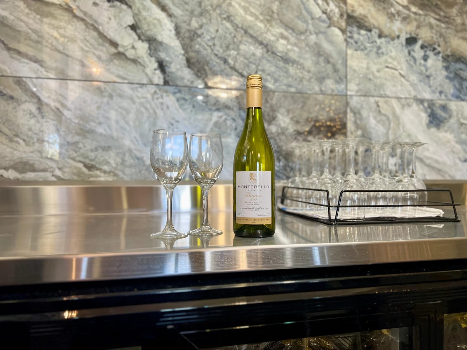 Montebello wine bottle and glasses on slate counter with stone wall behind