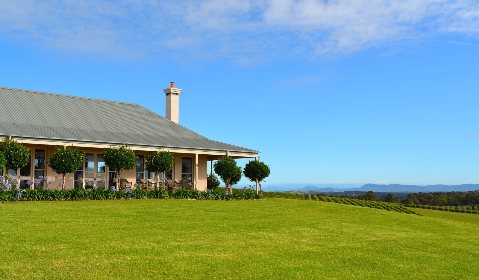 Cream-coloured manor house with metal roof on green grounds