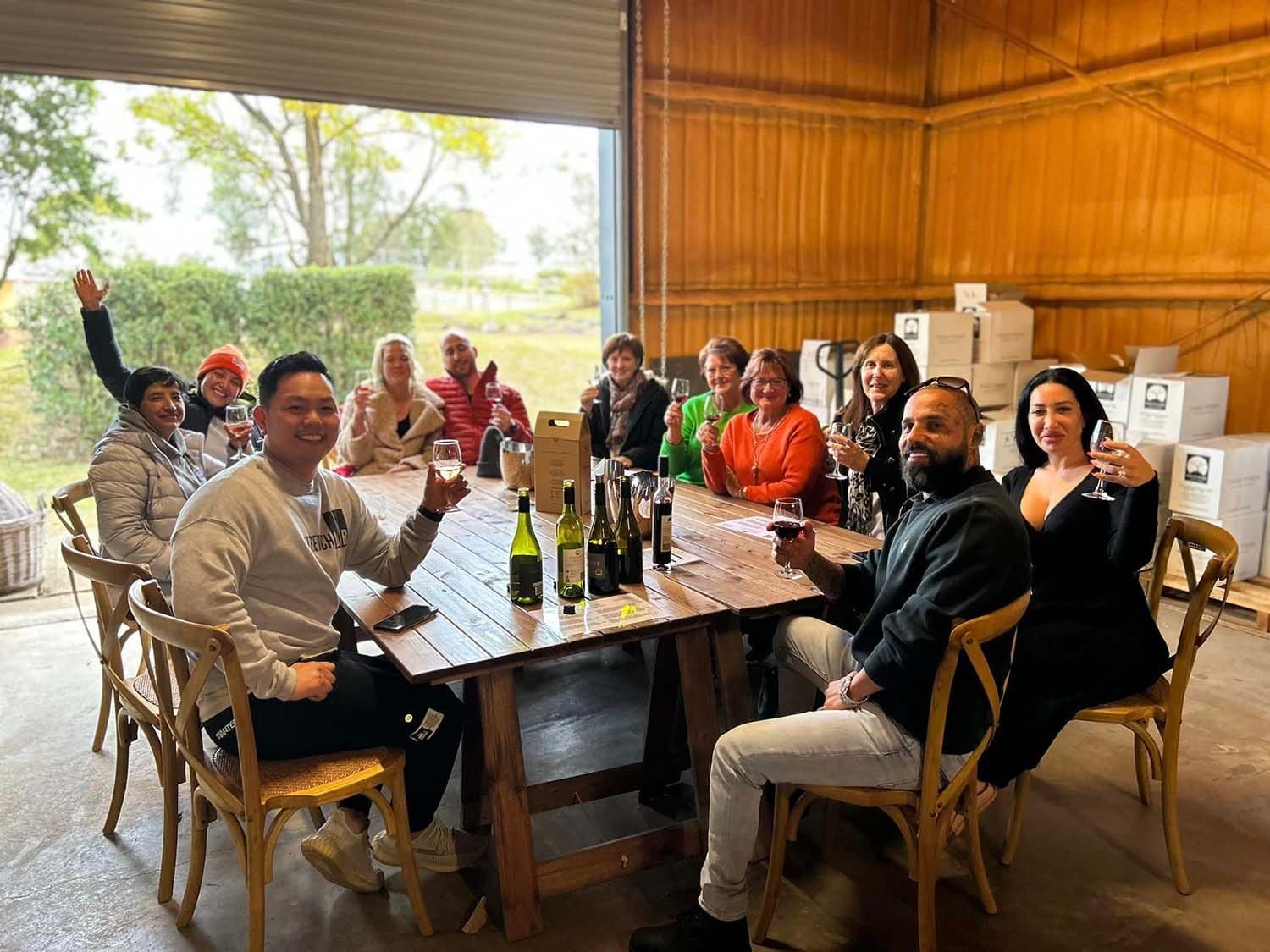 Large group wine tasting gathering in timber barn with vineyard view