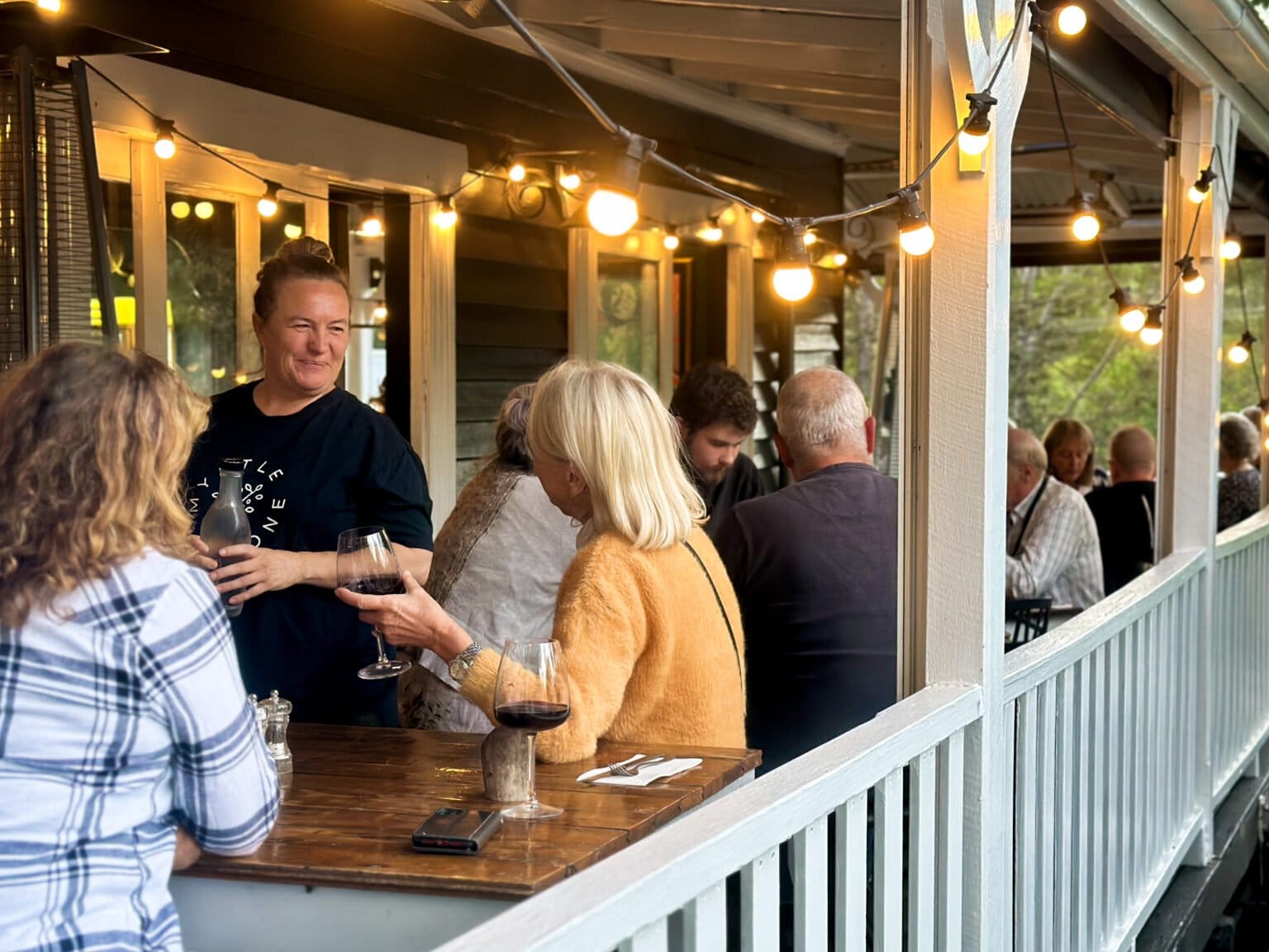 Guests chatting over wine on the Myrtle and Stone verandah at dusk