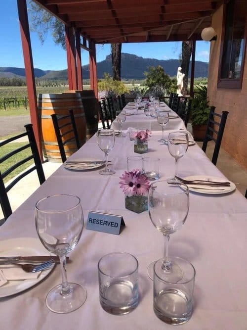 Outdoor dining table under red pergola with vineyard outlook