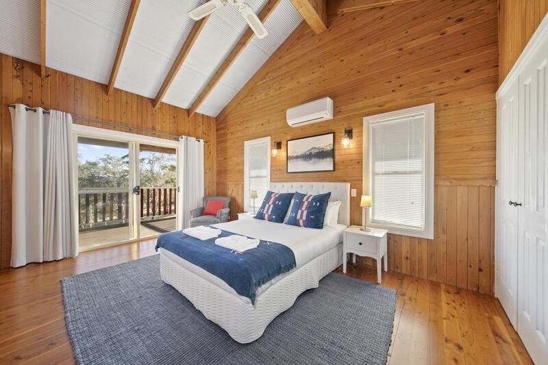 Timber-lined bedroom with balcony doors at North Lodge Estate Cottages