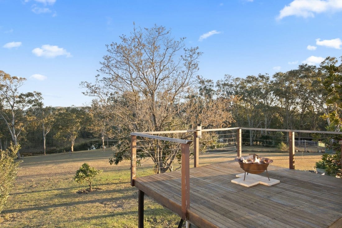 Timber deck with a fire pit and open lawn at North Lodge Estate Cottages, Pokolbin