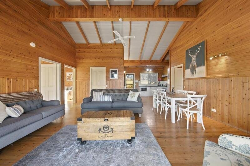 Timber-lined living area with sofas and a dining table at North Lodge Estate Cottages