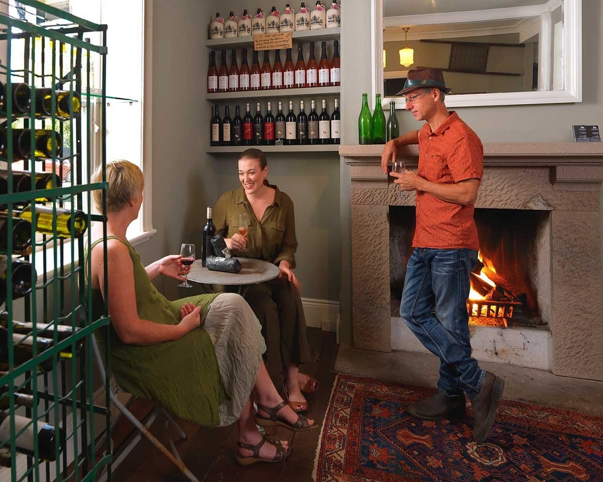 Host and visitor tasting wine in front of fireplace