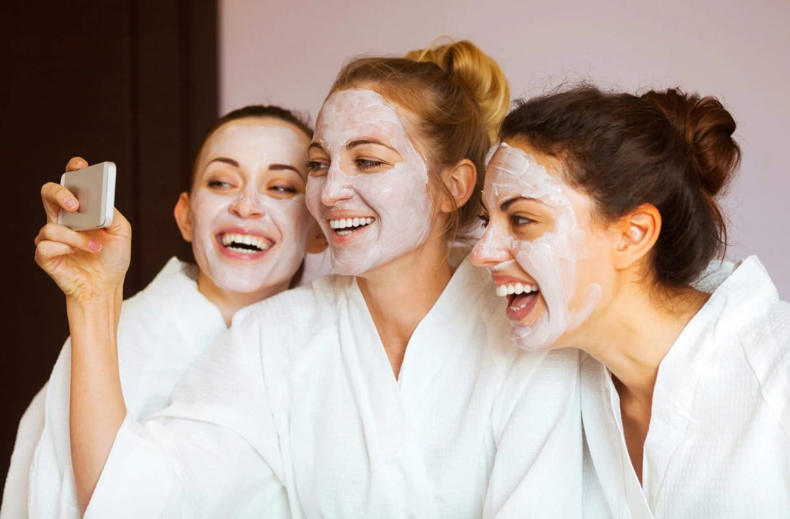 Three people with white face masks taking selfie at spa