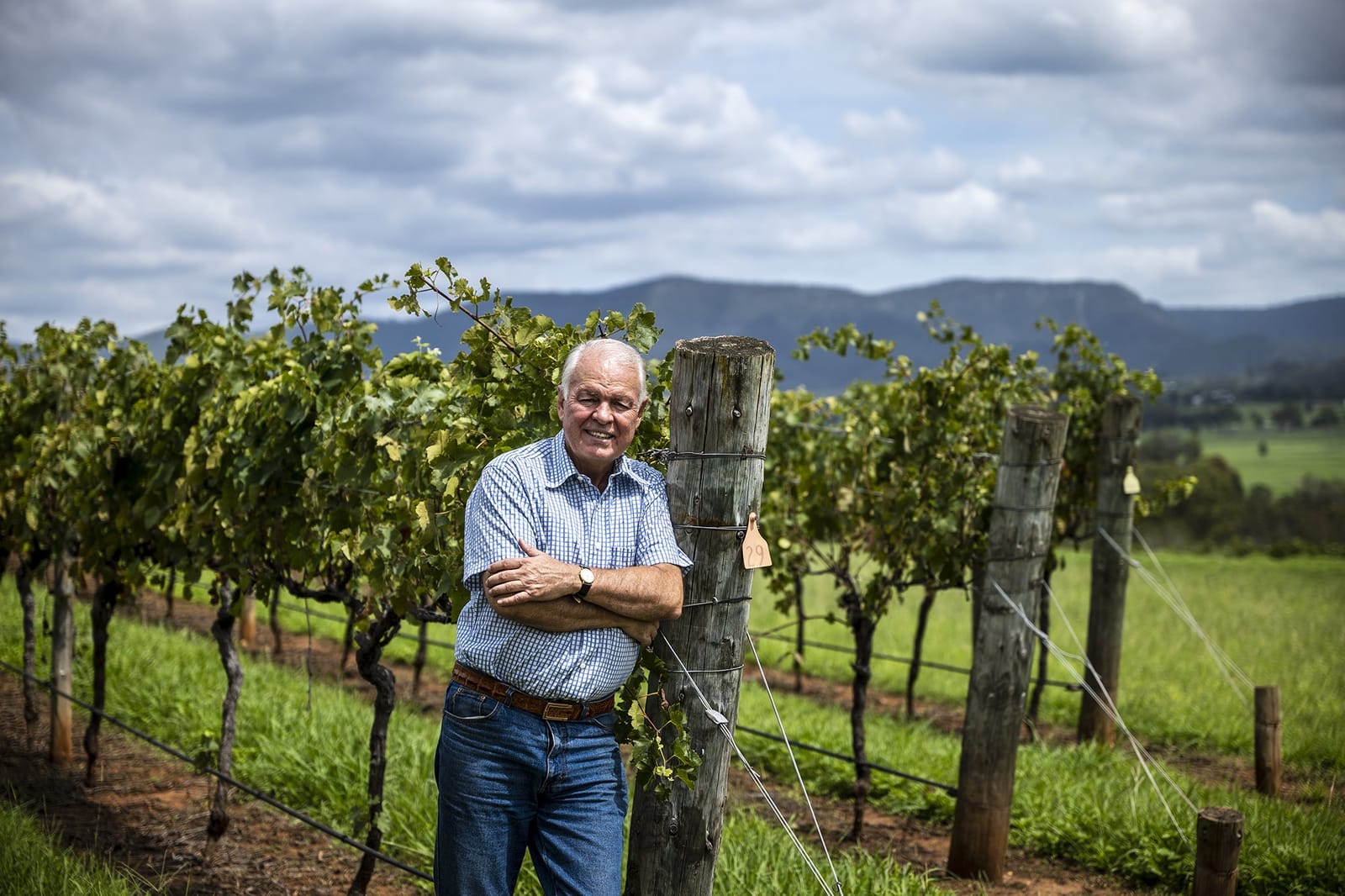 Vigneron Richard Becker leaning on a vineyard post with the Brokenback Range behind