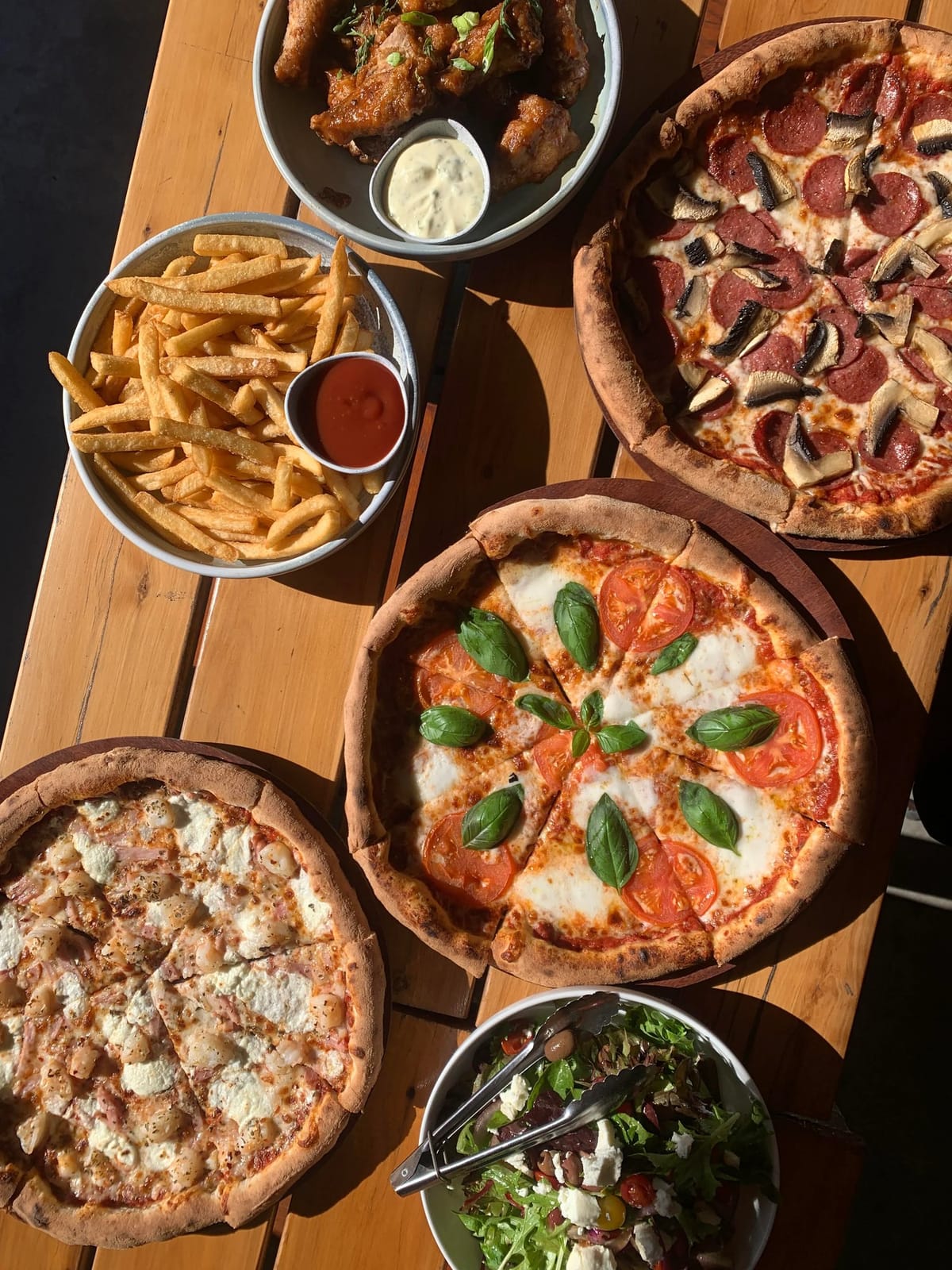 Italian pizzas, fried chicken, and fresh salad overhead