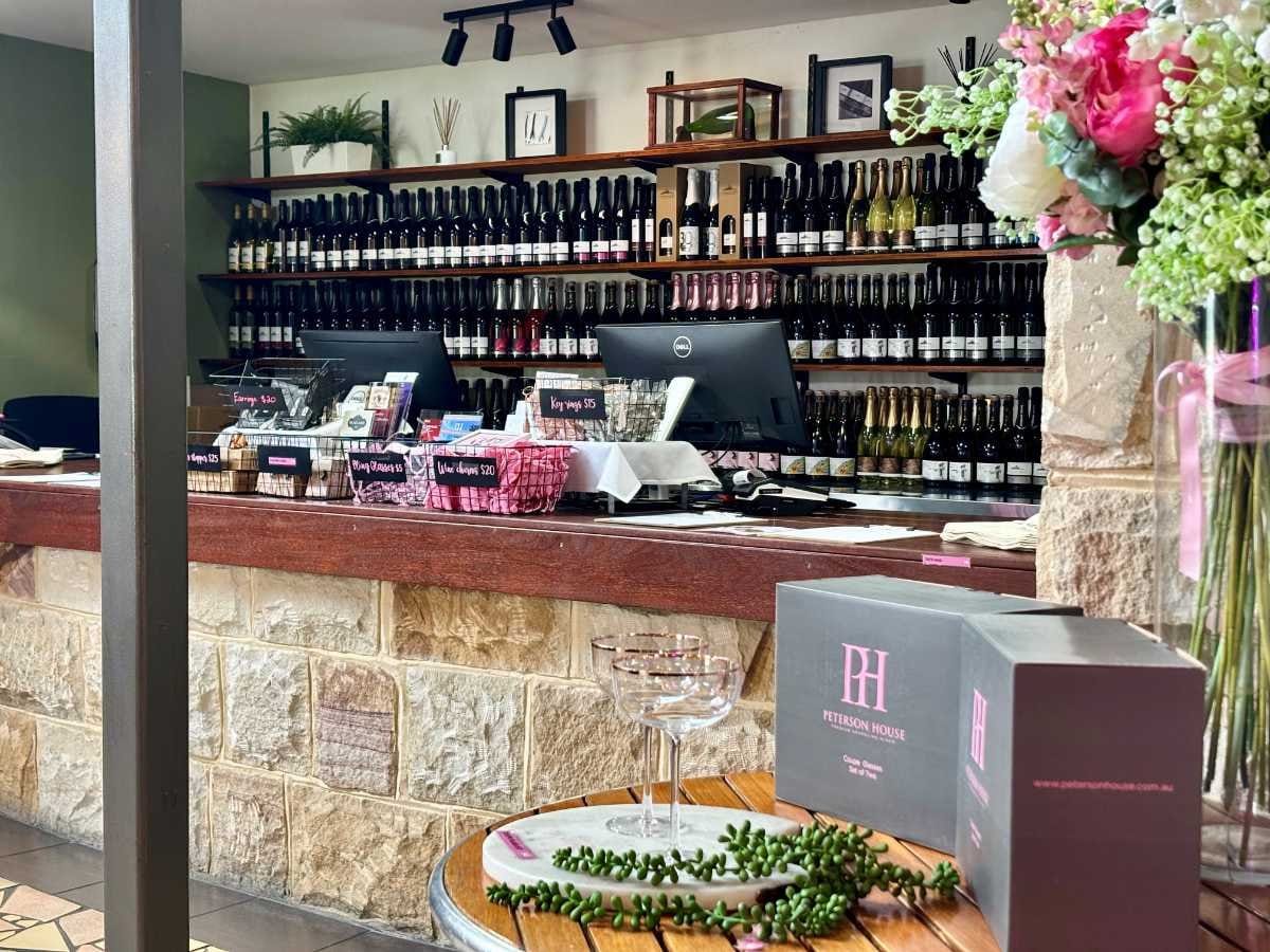 Tasting counter with wine bottles displayed on shelves and merchandise
