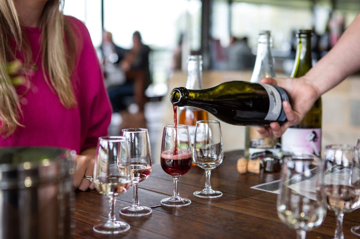 Red wine being poured into tasting glasses during a flight experience