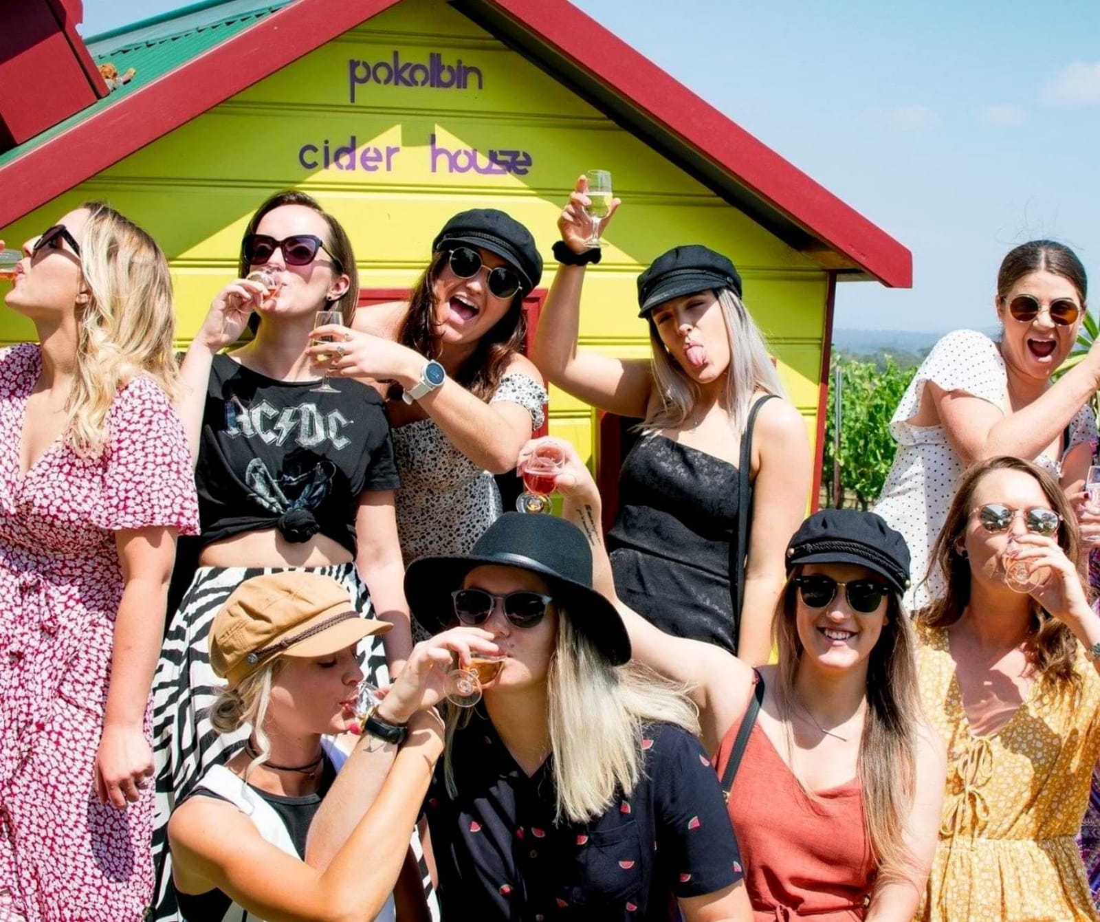 Visitors with tasting glasses outside yellow and red Cider House at Pokolbin Cider House, Pokolbin, Hunter Valley