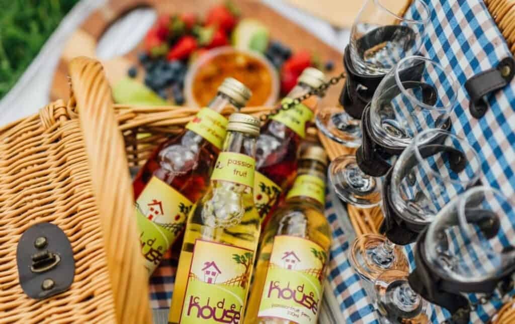 Cider bottles and glasses packed into a picnic basket with fruit