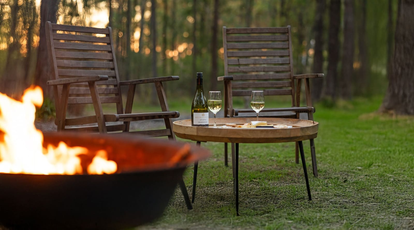 Fireside chairs and wine board beside outdoor firepit at Pokolbin Cottages, Pokolbin, Hunter Valley