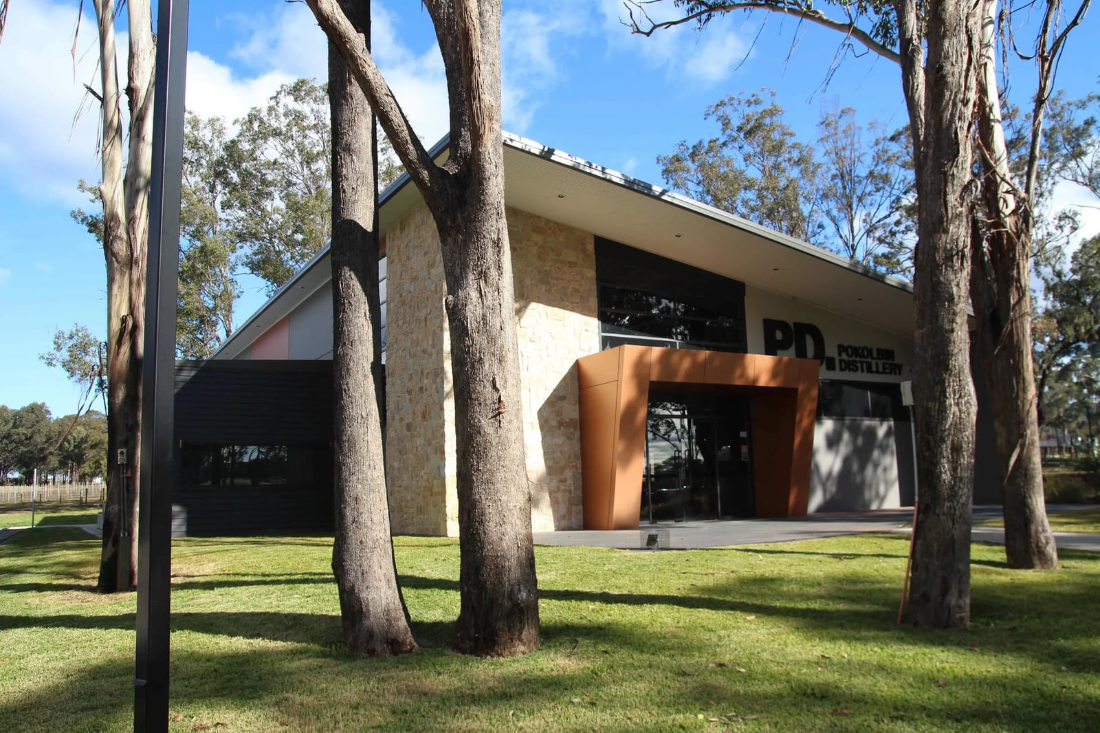 Modern stone distillery building with eucalyptus trees at Pokolbin Distillery, Hunter Valley