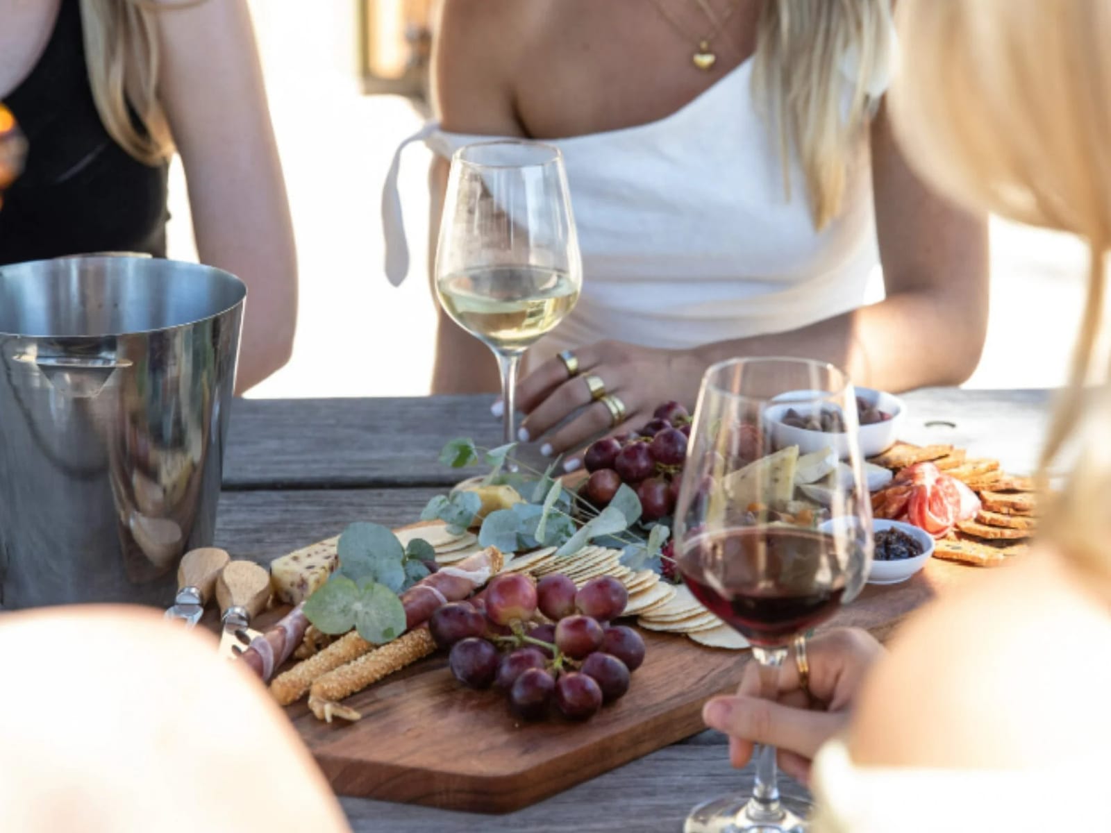Woman holding wine glass with snacks and companions